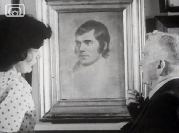 Black and white image, two people look at a portrait of Robert Burns